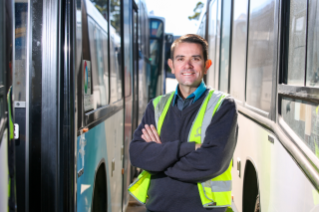 Male Transport Services VET Standing Between Buses Smiling Into Camera